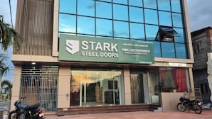 Un edificio con un amplio muro de vidrio, un cartel que dice 'STARK STEEL DOORS' y una zona de recepción.