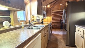 A kitchen with wooden cabinets, a stainless steel refrigerator, a dishwasher, and a sink. - Yodeling Loon Hideaway 3 Bedroom Home (Cable)