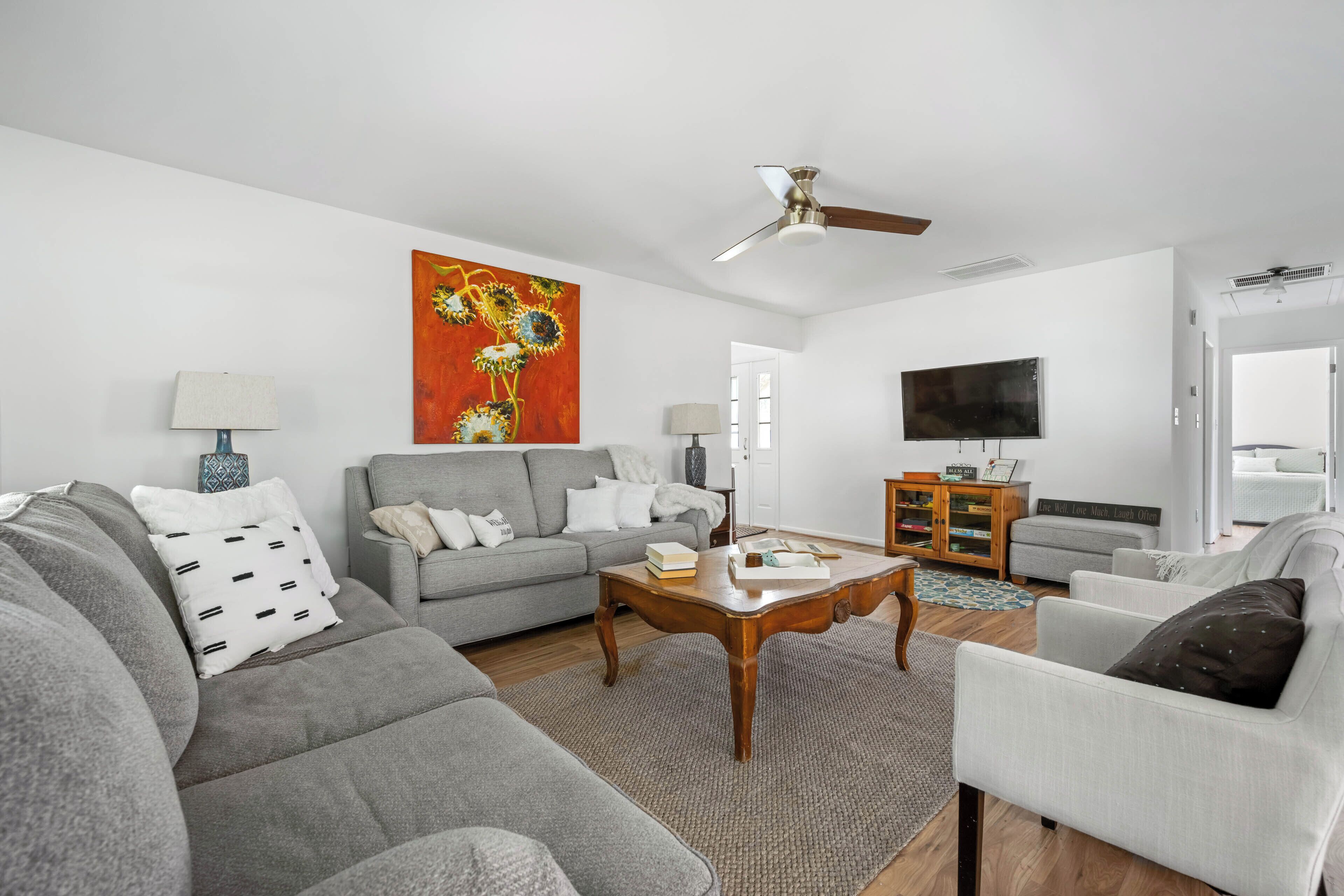 A living room with a grey sofa, a coffee table, a TV, and a ceiling fan.