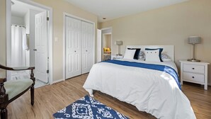 Een slaapkamer met een bed, een stoel, een nachtkastje en een lamp.