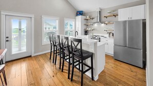 Una cocina moderna con una isla central, armarios blancos y un refrigerador de acero inoxidable.