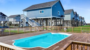 Zona residencial con piscina, terraza de madera y casas con balcones.