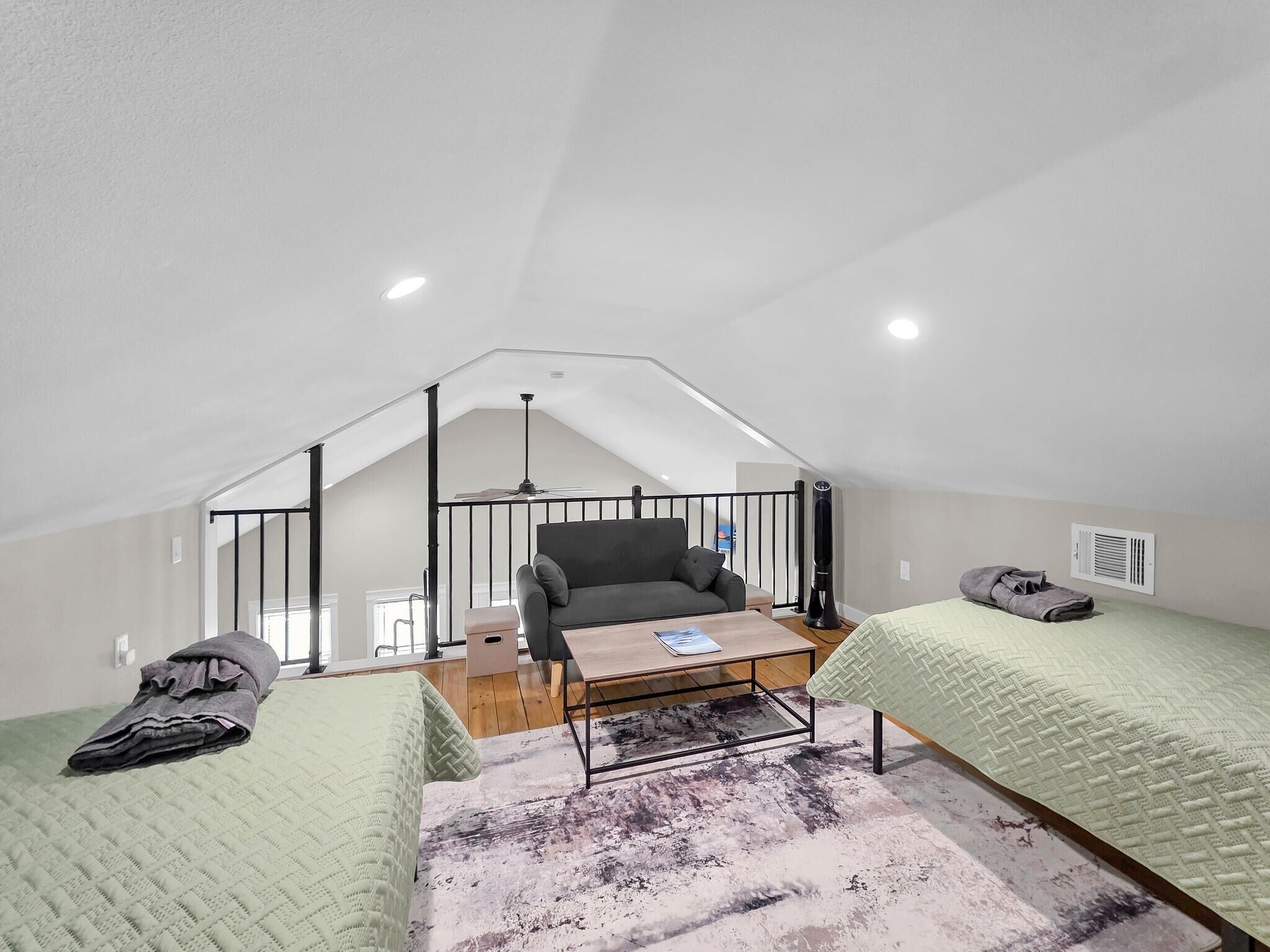 Un dormitorio tipo loft con techo inclinado, un sofá, una mesa de centro y dos camas.