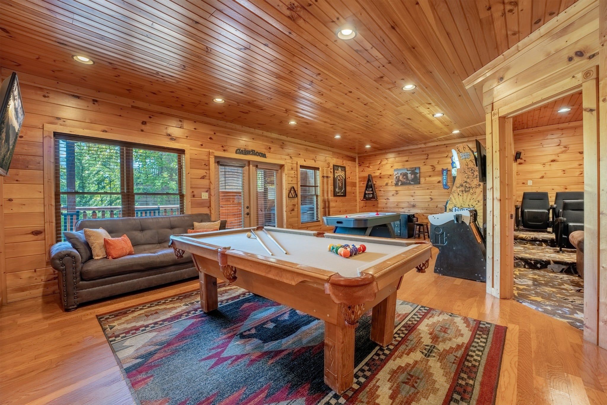 A wooden interior with a pool table, a sofa, and a bar area.