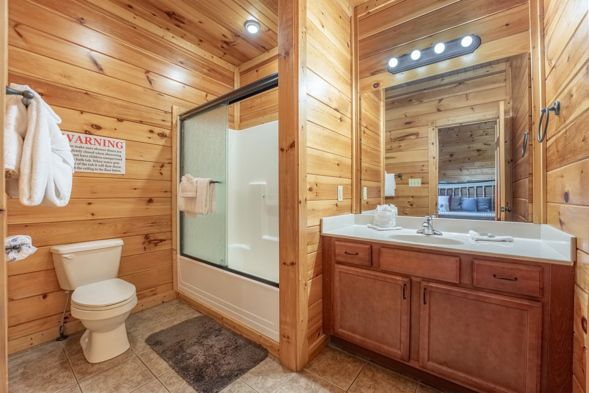 Un baño de cabaña de madera con inodoro, ducha y lavamanos.