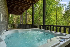 Un jacuzzi en una terraza de madera con vistas a un bosque.