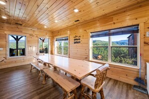 A wooden cabin with a large dining table, benches, and large windows offering mountain views. - Gatlinburg Views Lodge 5 Bedroom Cabin (Gatlinburg)