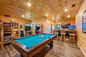 A wooden interior with a pool table, arcade games, and a television. - Gatlinburg Views Lodge 5 Bedroom Cabin (Gatlinburg)