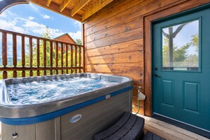 Ein Whirlpool auf einer Holzterrasse, im Hintergrund eine Tür und ein Fenster.