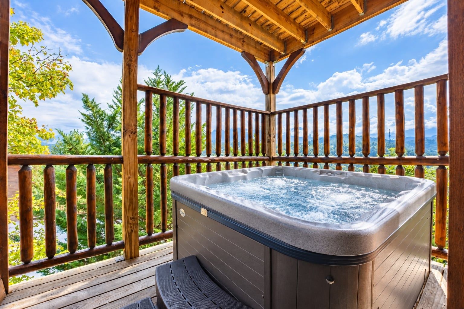 A hot tub on a wooden deck with a view of trees and mountains.