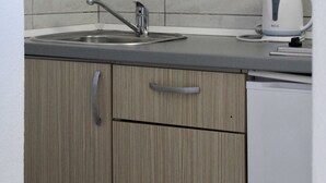 A kitchen with wooden cabinets, a sink, and a kettle. - Apartments Jozo Baška Voda (Baska Voda)
