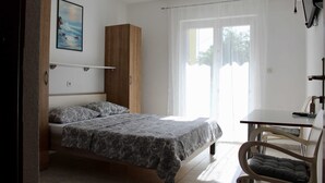 A bedroom with a bed, a wooden wardrobe, a desk with a chair, and a window with curtains. - Apartments Jozo Baška Voda (Baska Voda)