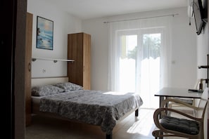 A bedroom with a bed, a wooden wardrobe, a desk with a chair, and a window with curtains. - Apartments Jozo Baška Voda (Baska Voda)
