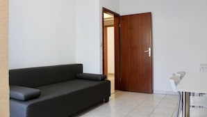 A room with a dark-colored sofa, a wooden door, and a white table. - Apartments Jozo Baška Voda (Baska Voda)