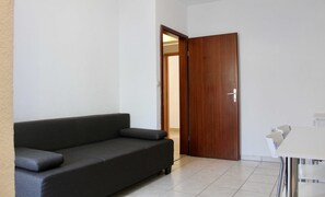 A room with a dark-colored sofa, a wooden door, and a white table. - Apartments Jozo Baška Voda (Baska Voda)
