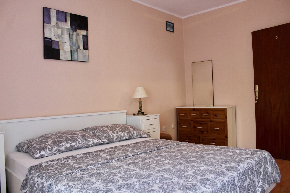Un dormitorio con cama, cómoda, lámpara y un cuadro en la pared.