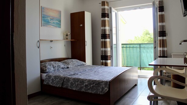 A bedroom with a bed, a wooden wardrobe, a table, and a chair. - Apartments Jozo Baška Voda (Baska Voda)