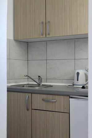 A kitchen with wooden cabinets, a sink, and a kettle. - Apartments Jozo Baška Voda (Baska Voda)