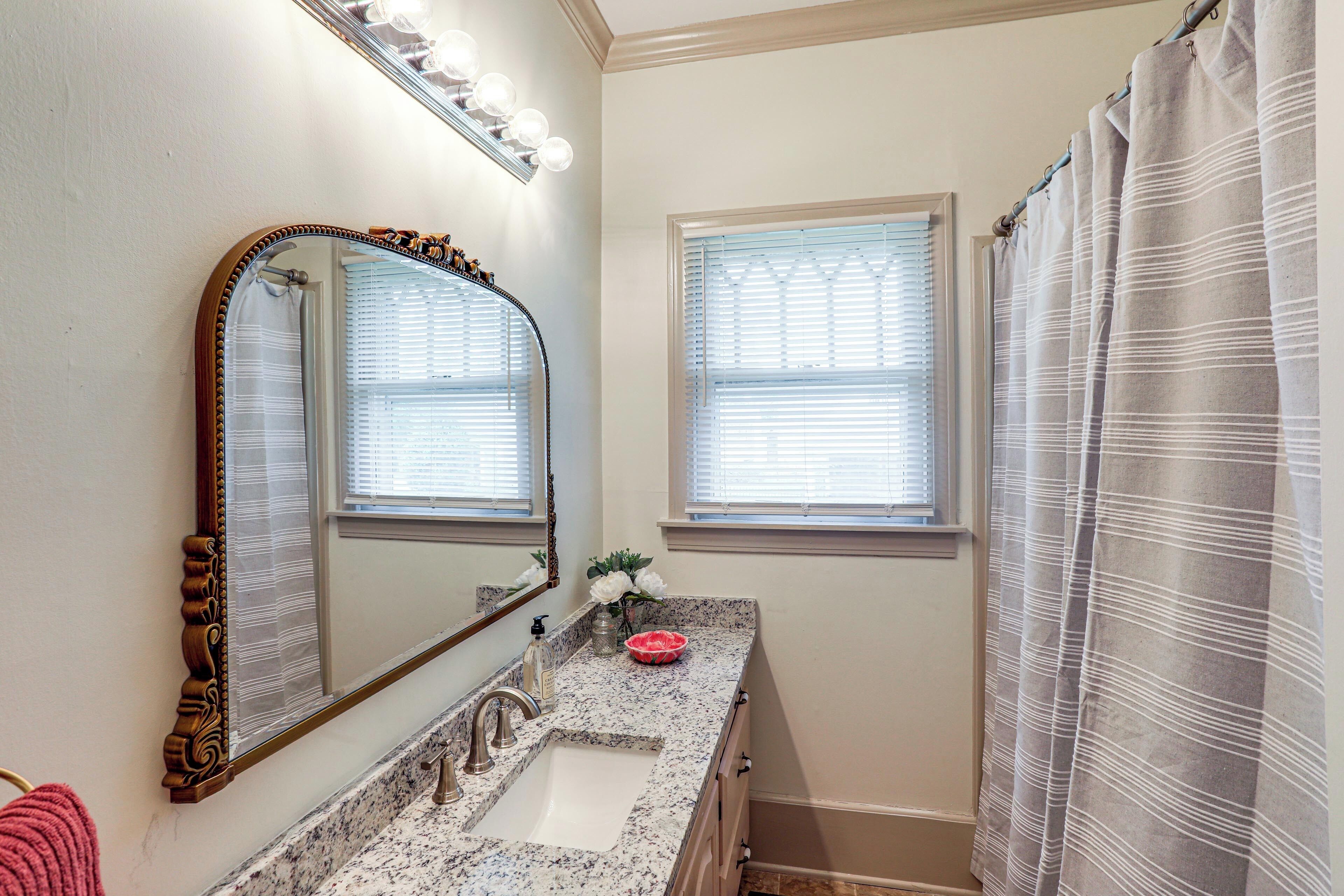 A bathroom with a marble sink, a large mirror, and a shower curtain.