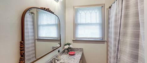 A bathroom with a marble sink, a large mirror, and a shower curtain.