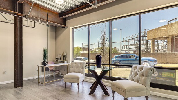A spacious room with large windows, a glass partition, and a dining area with chairs and a table. - Explore the City! Walkable Lawrenceville Condo (Pittsburgh)