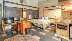 A hotel room with a bed, a desk with a computer, a television, a microwave, and a small kitchenette. - Warrior Trail Access! Converted Schoolhouse Suite (Gary)
