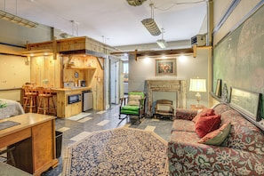 A cozy room with a wooden dining area, a green rocking chair, a patterned rug, and a fireplace. - Warrior Trail Access! Converted Schoolhouse Suite (Gary)