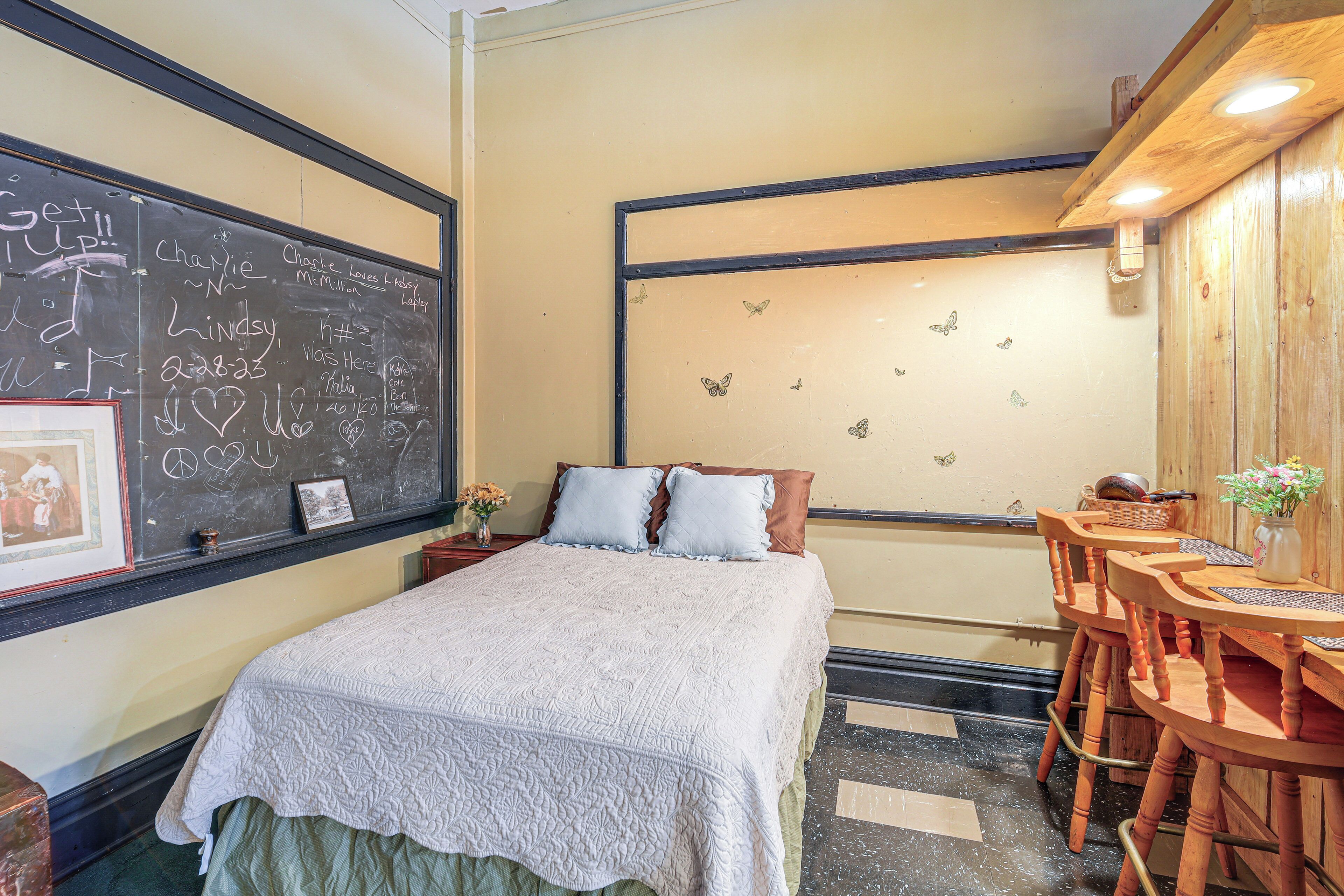 Una habitación con cama, escritorio y una pizarra con inscripciones.