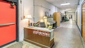 A reception desk with a 'Please Sign In' sign, a lamp, a chair, a piano, and a door with a red frame. - Warrior Trail Access! Converted Schoolhouse Suite (Gary)