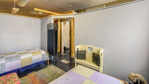A room with two beds, a bench, and a door leading to another room. - Warrior Trail Access! Converted Schoolhouse Suite (Gary)