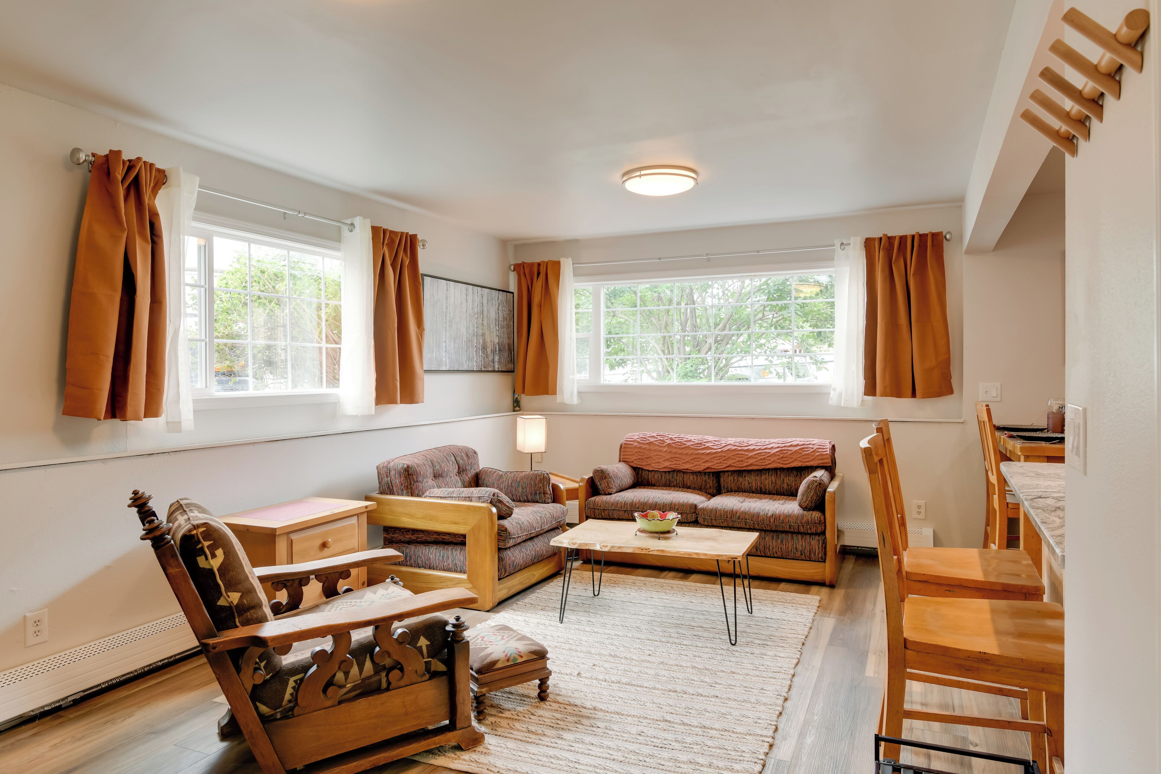 A spacious living room with a sofa set, a wooden coffee table, and a dining area with wooden chairs and a table.