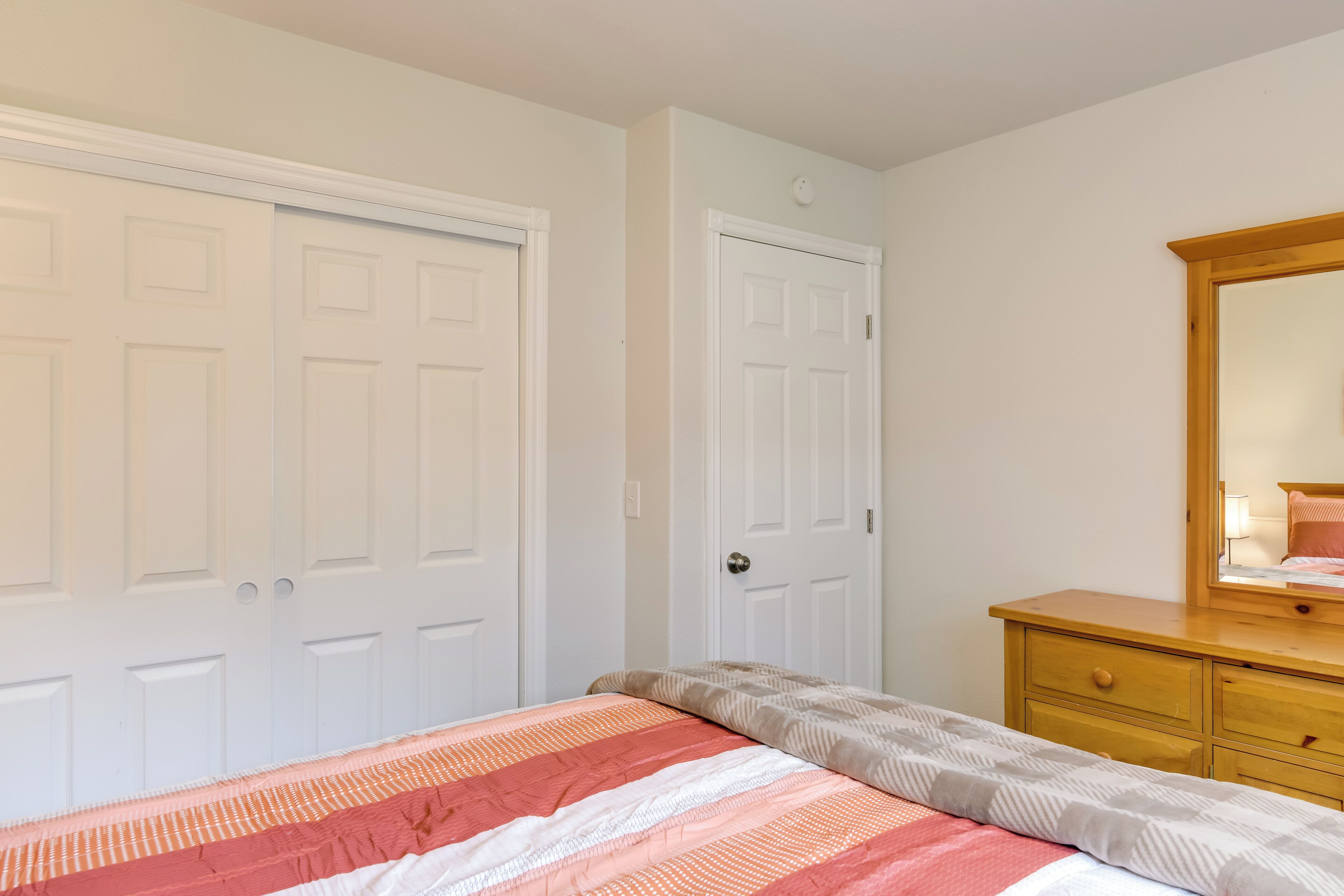Une chambre à coucher avec un lit, une commode et deux portes.