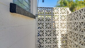 A white wall with a decorative metal fence featuring geometric patterns. - Beach-hop, Bike & Bbq! Clearwater Home w/ Yard (Clearwater)