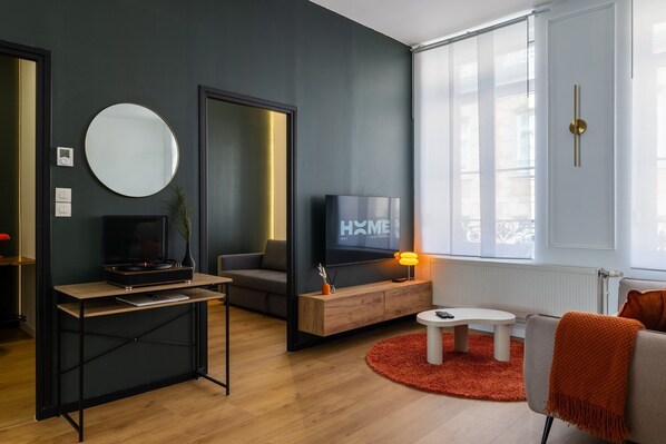 Un salon moderne avec un téléviseur, un canapé, une table basse et une cheminée.