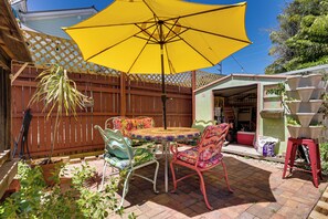 Eine Terrasse mit Tisch und Stühlen, einem gelben Sonnenschirm und einem Holzzaun.
