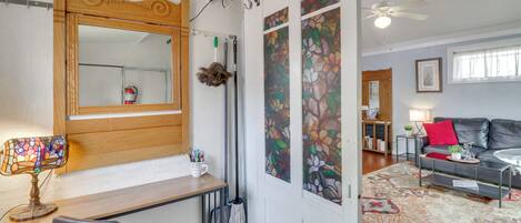 A room with a wooden desk, chair, mirror, and a large window with floral artwork.