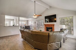 A modern living room with a leather sofa, a fireplace, and a TV mounted above it. - 6 Mi to Epic Waters! Spacious Family Getaway (Grand Prairie)