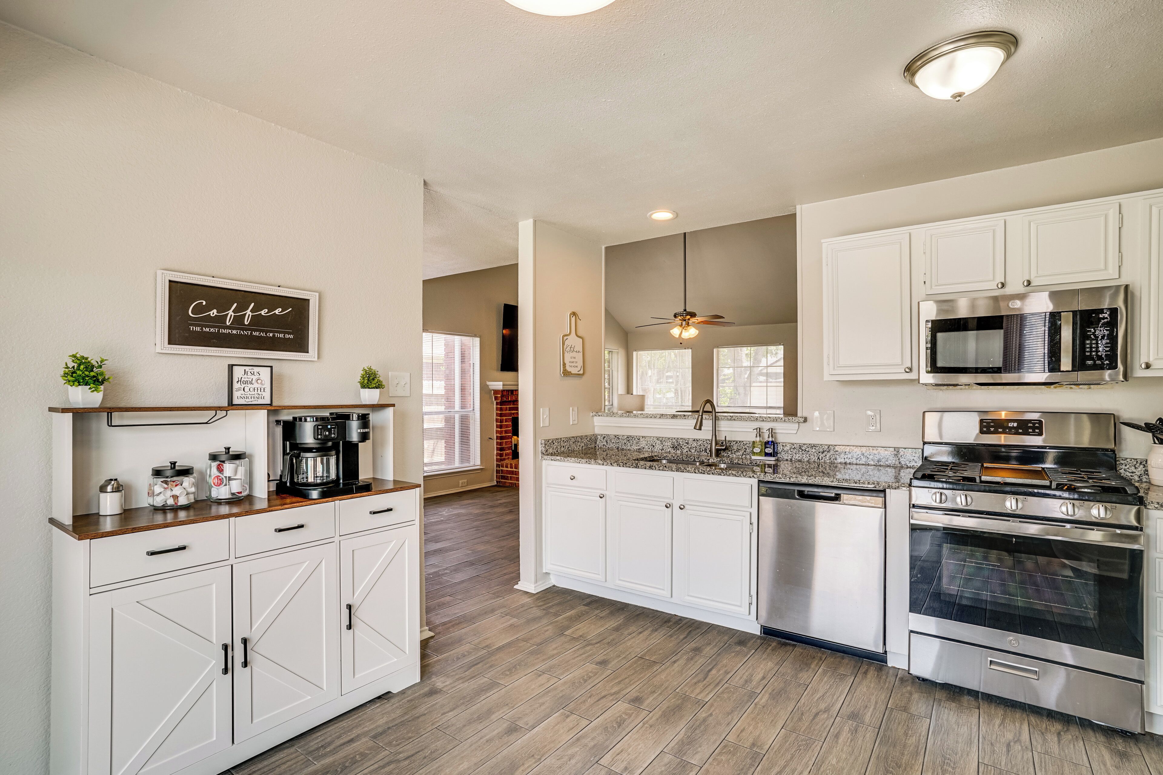 A kitchen with white cabinets, a stainless steel oven, a microwave, and a coffee maker.