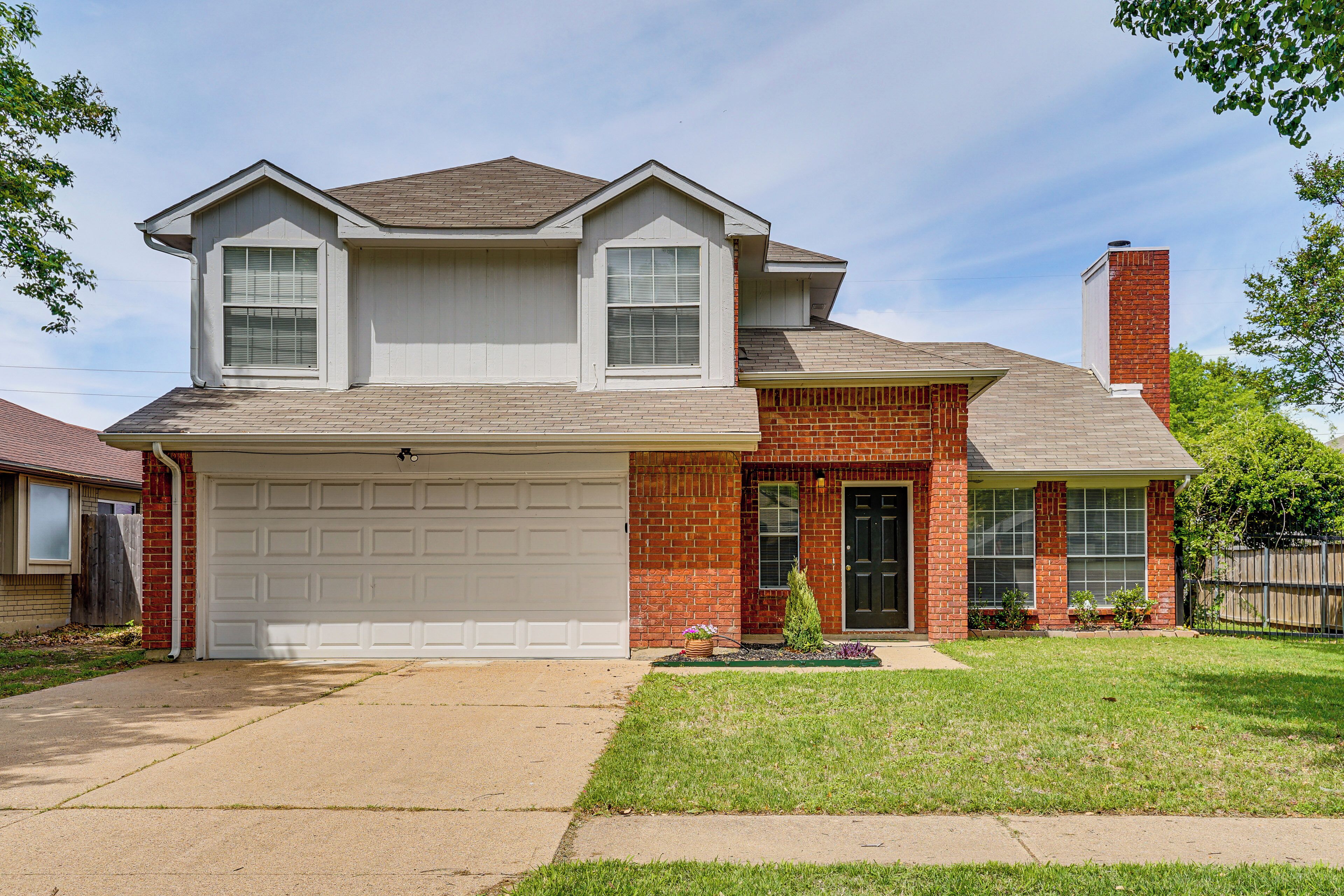 A two-story house with a garage, a brick facade, and a front door.