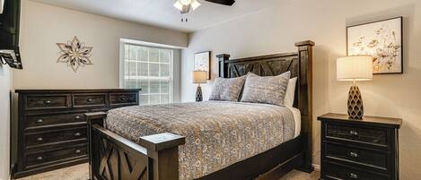 A bedroom with a bed, a nightstand, a ceiling fan, and a window.
