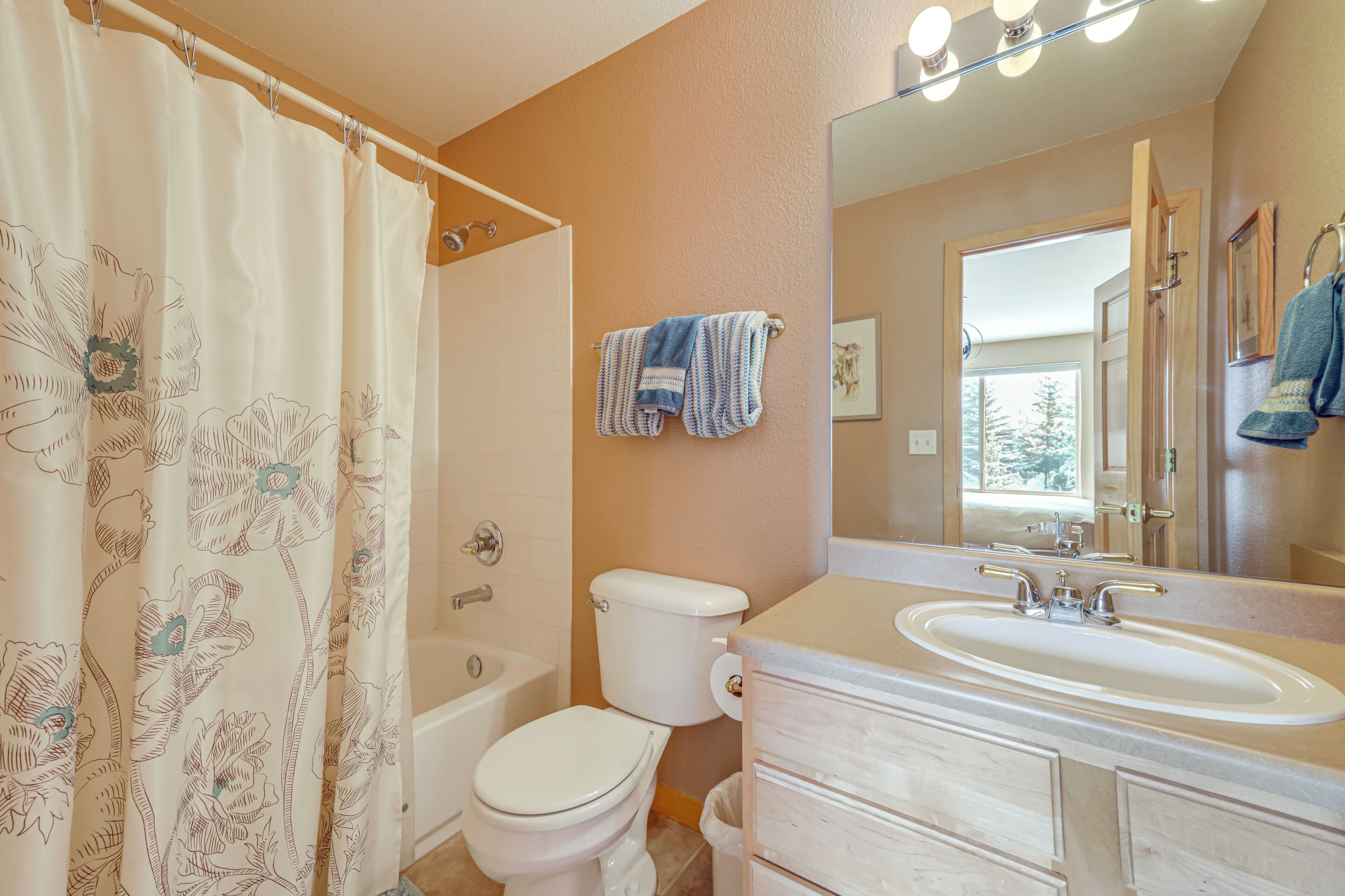A bathroom with a shower curtain, toilet, sink, and vanity.