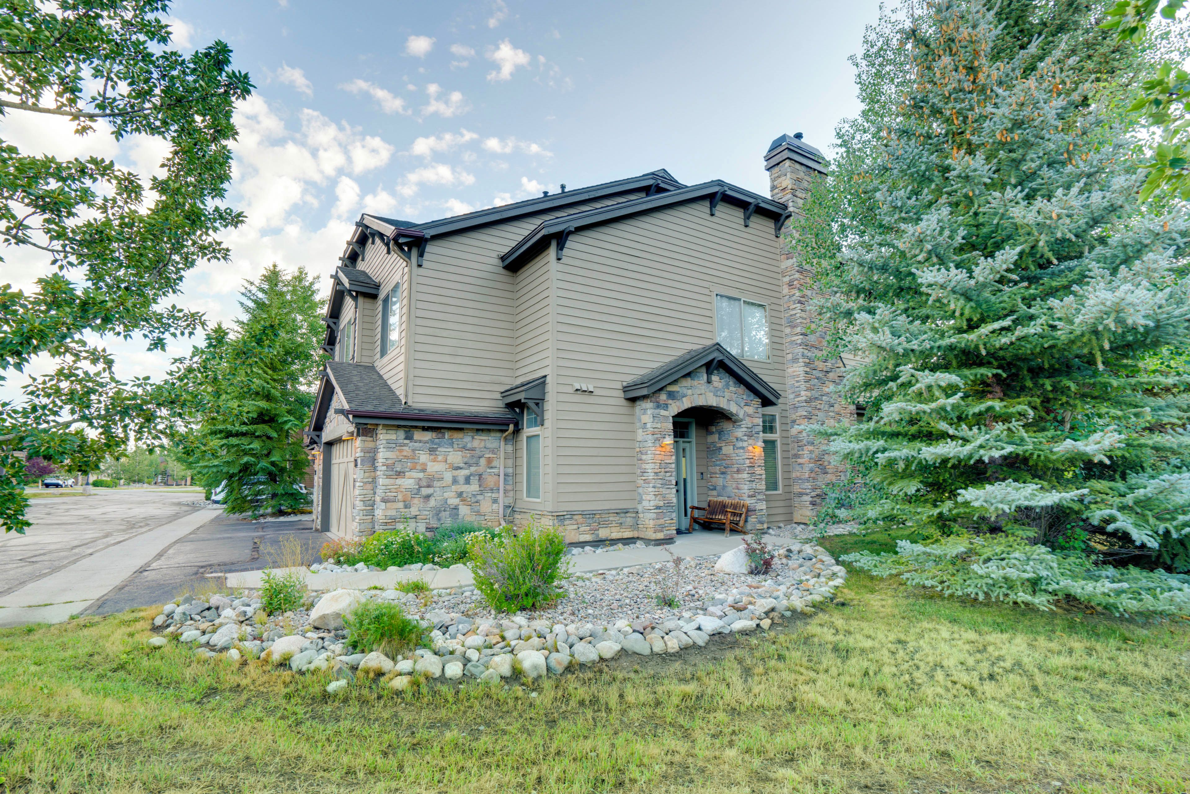 A two-story house with a stone facade and a stone chimney.