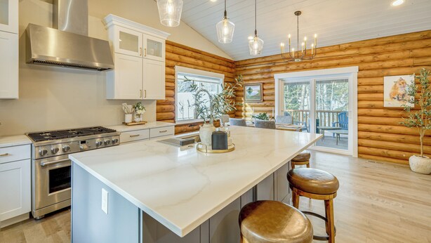 A kitchen with a large island, stainless steel appliances, wooden walls, and pendant lighting. - Luxury Mccall Lodge: Hike, Ski, Golf & More! (McCall)