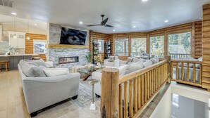 A spacious living area with a fireplace, a wooden deck, and a view of the outdoors. - Luxury Mccall Lodge: Hike, Ski, Golf & More! (McCall)