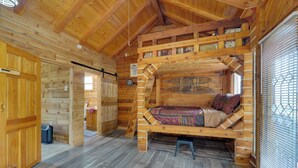 Interior acogedor de una cabaña de troncos con una cama en el altillo, paredes de madera y una pequeña kitchenette.