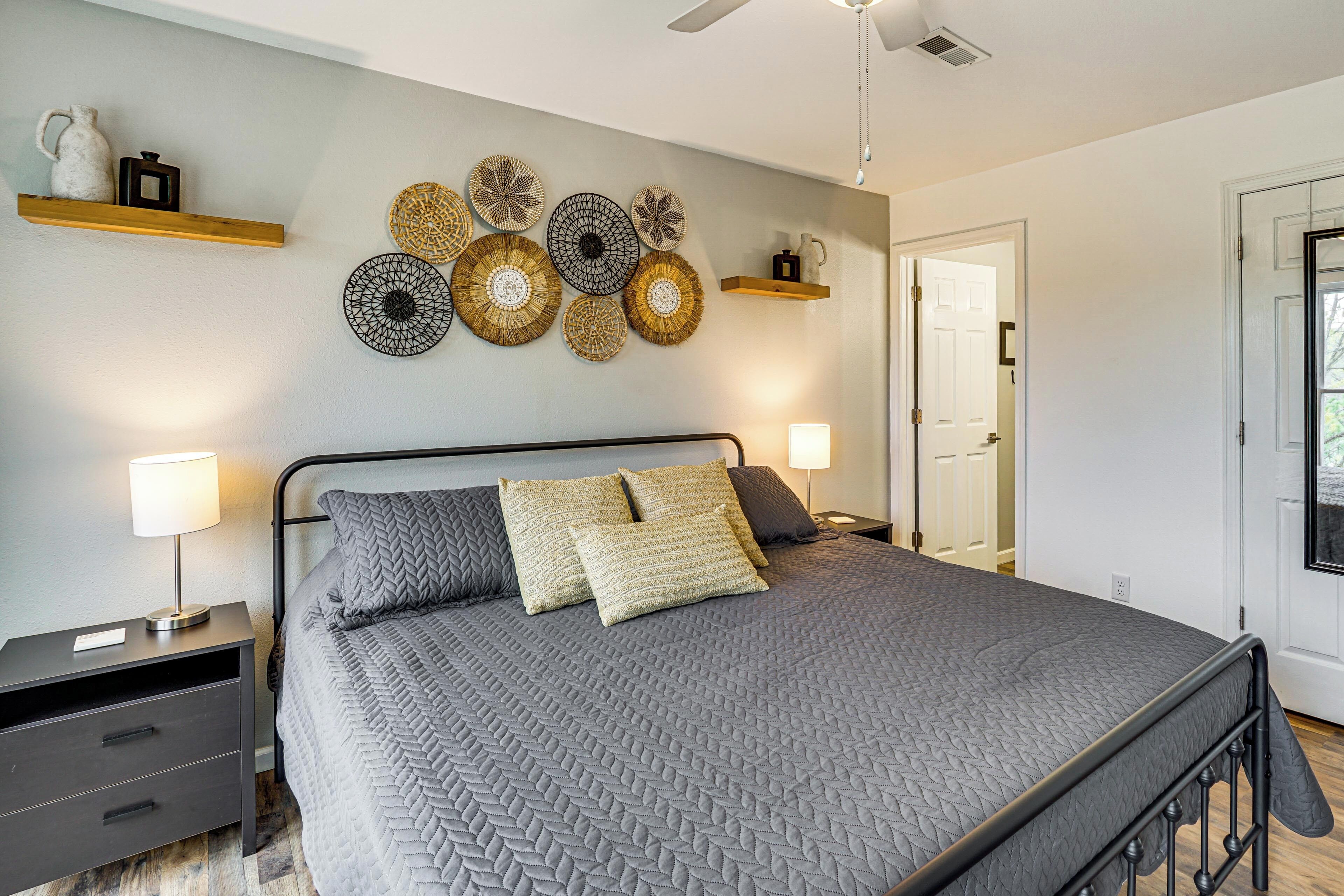 A bedroom with a bed, bedside tables, wall decor, and a door.