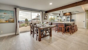 Un comedor amplio con una mesa y sillas grandes, una cocina con electrodomésticos modernos y vistas a través de un ventanal.