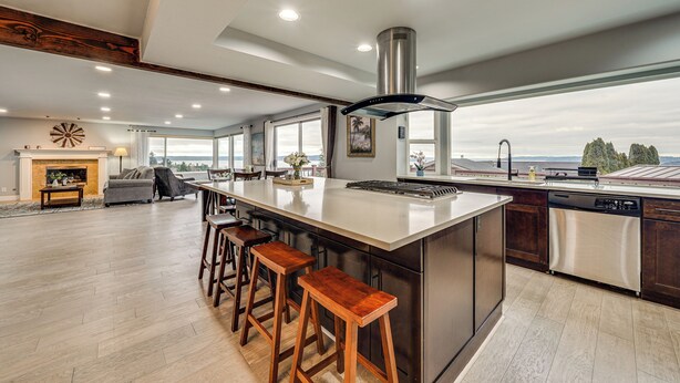 Una cocina amplia con una isla grande, taburetes de bar, horno empotrado y vistas al exterior.