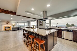 A spacious kitchen with a large island, bar stools, a built-in oven, and a view of the outdoors. - Puget Sound Views! Serene Federal Way Retreat (Federal Way)