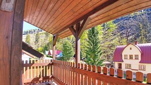 Un balcon en bois donnant sur une maison et des arbres.